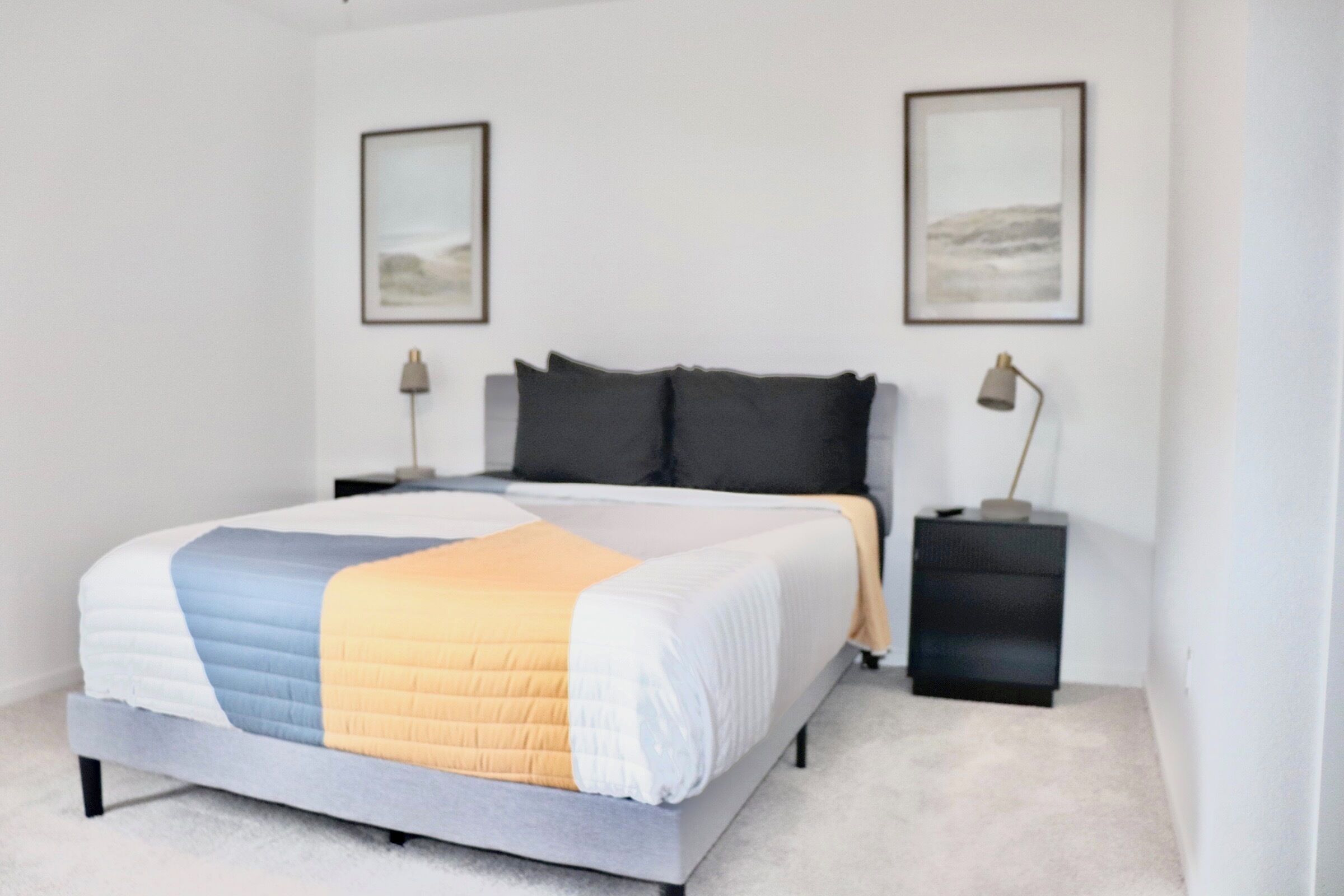 A bedroom with a bed, two bedside tables, and two wall-mounted lamps.