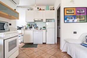 A compact kitchen with white cabinetry, a built-in oven, and a refrigerator.