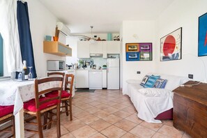 A compact living space with a dining area, kitchenette, and a sofa with cushions.