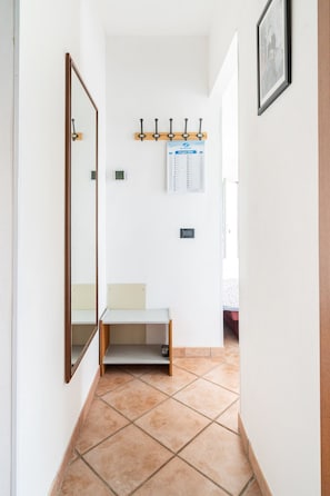 A hallway with a wooden bench, a wall-mounted calendar, and a mirror.