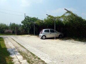 A gravel road with a parked car and a sidewalk.