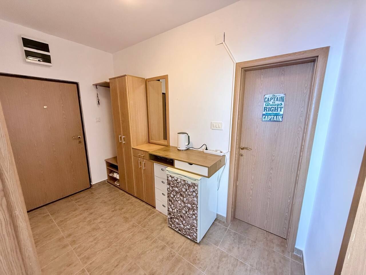 Una cocina compacta con un mueble de madera, lavavajillas integrado y una puerta con un letrero.