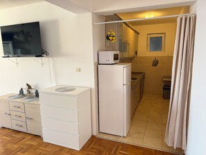 Eine kleine Küche mit Kühlschrank, Mikrowelle und Spüle.