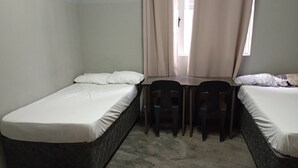 Un petit logement composé d’une seule pièce, comprenant deux lits simples, une table et des chaises.