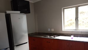 A kitchen with a refrigerator, a microwave, a window, and a sink. - Groups Accommodation (Durban)