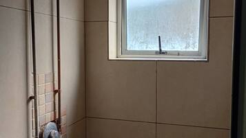 A bathroom with a shower, a window, and a towel rack.