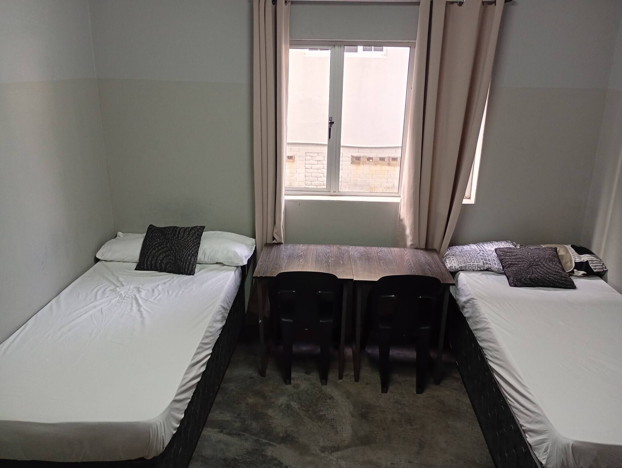 Une chambre avec deux lits simples, une petite table et des chaises.