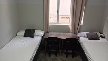 Une chambre avec deux lits simples, une petite table et des chaises.