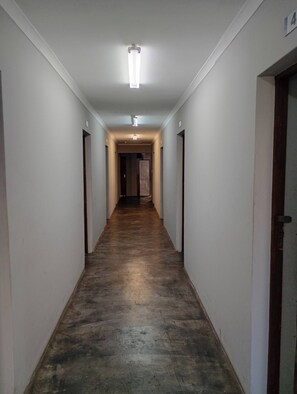 A narrow hallway with a wooden floor, white walls, and a ceiling light fixture.