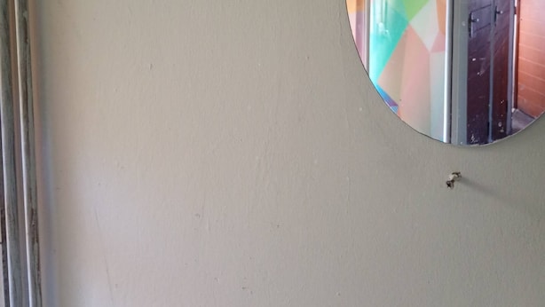 A round mirror on a wall with a visible reflection of a room. - Groups Accommodation (Durban)