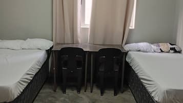 Une chambre avec deux lits, une petite table et deux chaises.