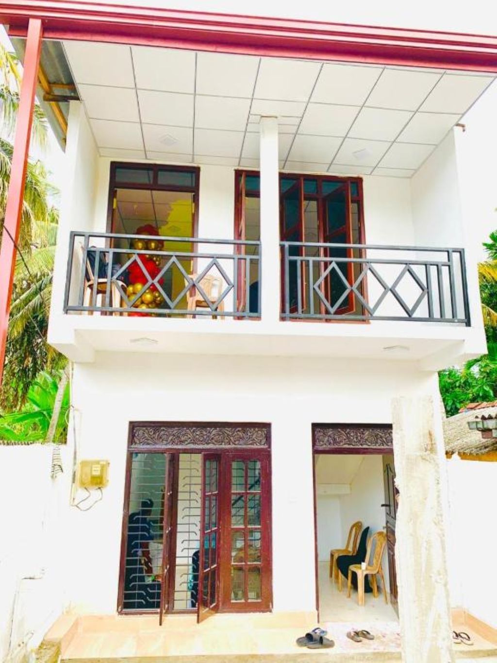 A two-story building with a balcony, a door with a decorative pattern, and a small porch area.