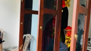 Una stanza con una porta in legno, una sedia e un pavimento piastrellato.