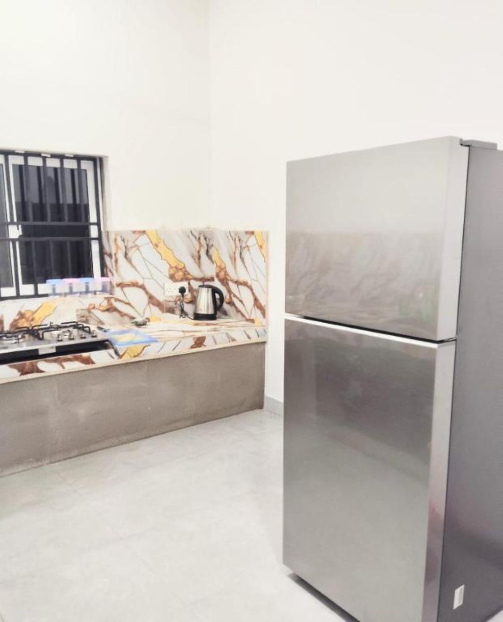 Una cocina con un refrigerador de acero inoxidable, una estufa a gas y un salpicadero de azulejos.