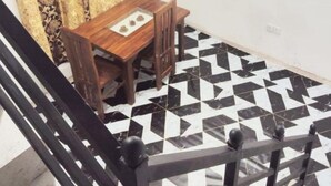 Zona pranzo con tavolo e sedie, tenda decorata e motivo geometrico sul pavimento.