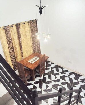 A dining area with a table and chairs, a patterned curtain, and a geometric floor pattern. - Cozy Home Stay - Wonderful 3-bedroom house with AC and with complete privacy (Wattala)