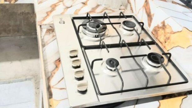 Una cucina con piano cottura a gas, zoccolo in marmo e ringhiera in metallo nero.