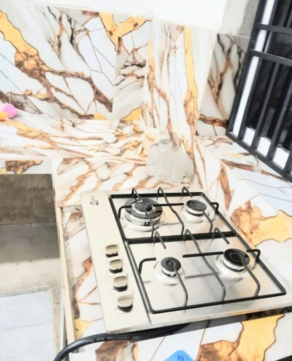 A kitchen with a gas stove, marble backsplash, and a black metal railing. - Cozy Home Stay - Wonderful 3-bedroom house with AC and with complete privacy (Wattala)