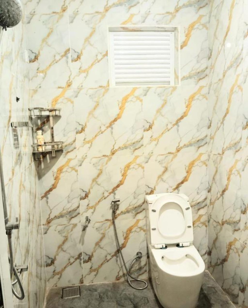 A bathroom with a toilet, shower, and marble walls.