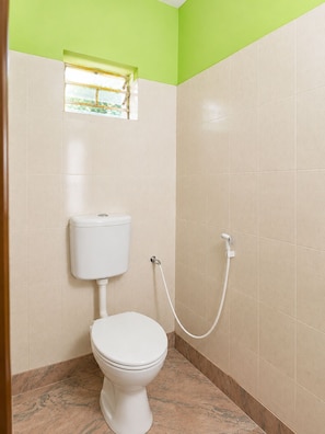 A bathroom with a toilet, a shower, and a window.