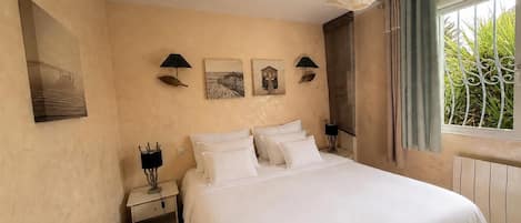 A hotel room with a large bed, two bedside tables with lamps, and artwork on the walls.