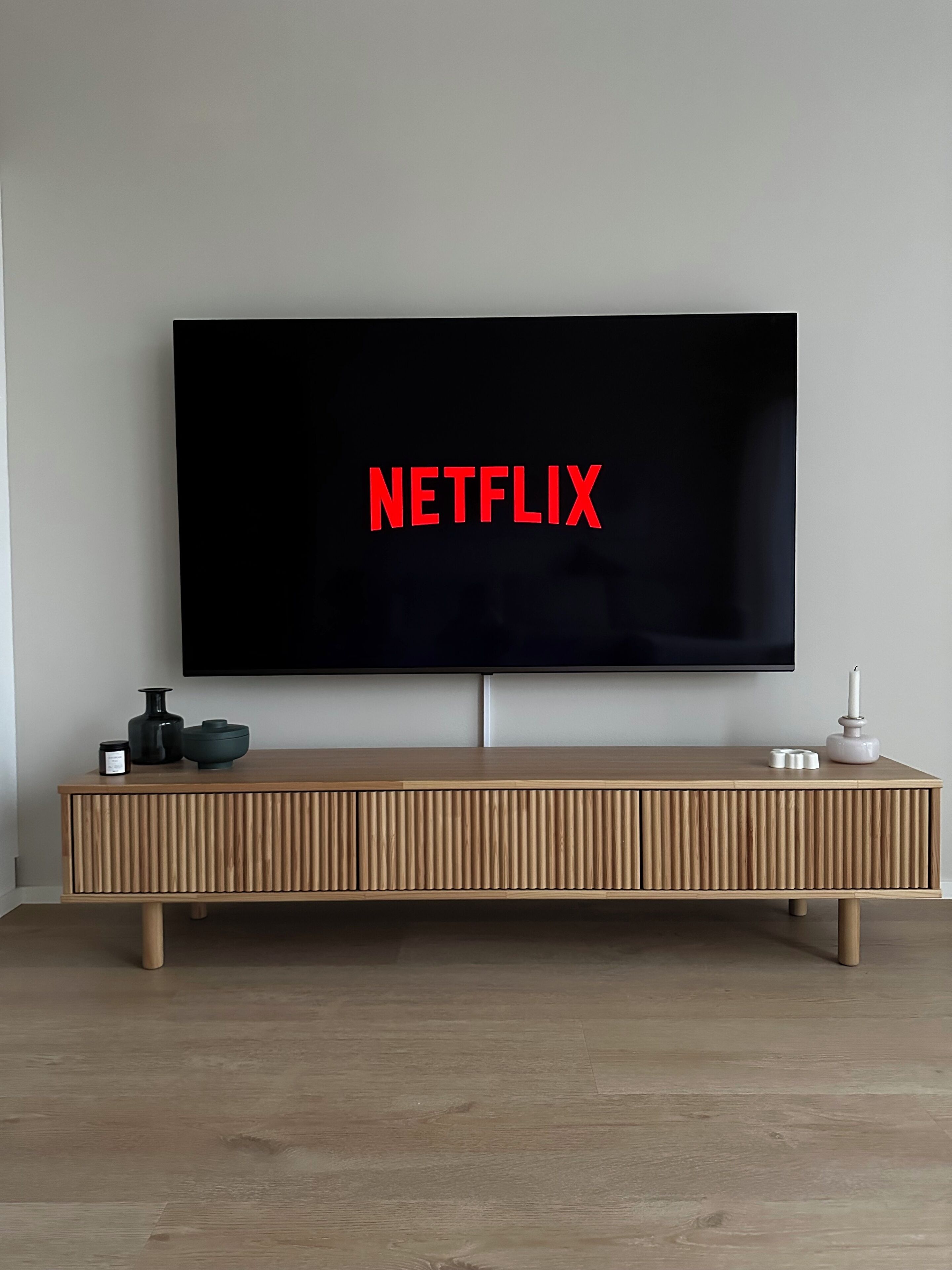 A flat-screen TV mounted on a wall with the word 'NETFLIX' displayed on the screen.