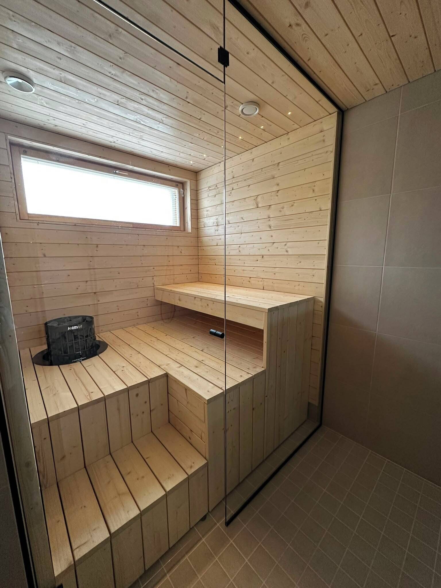 A sauna room with wooden walls, a bench, and a window.