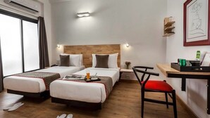 Habitación de hotel con dos camas, un escritorio, una silla y un ventanal.