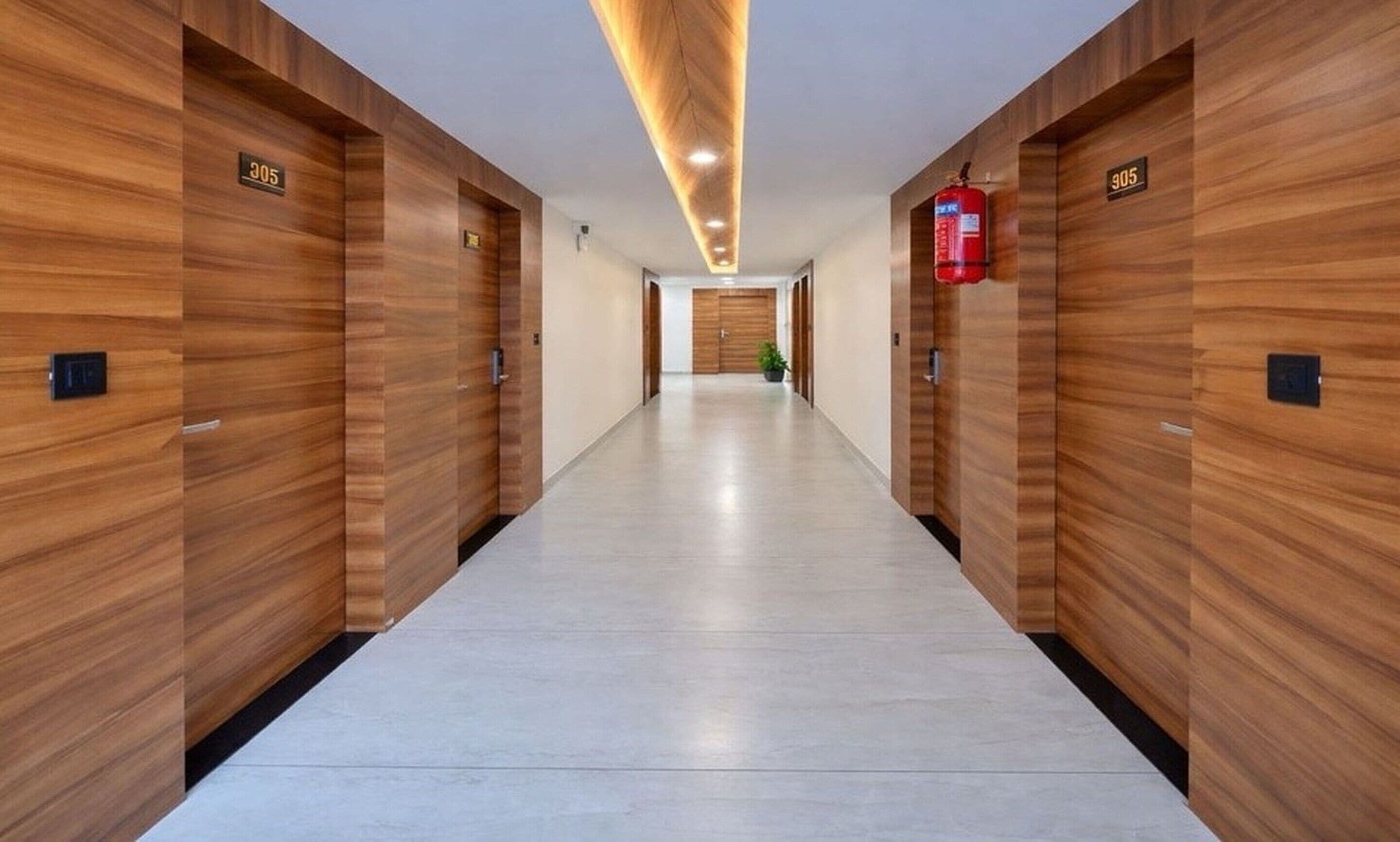 Un pasillo con paneles de madera, puertas numeradas y un extintor.