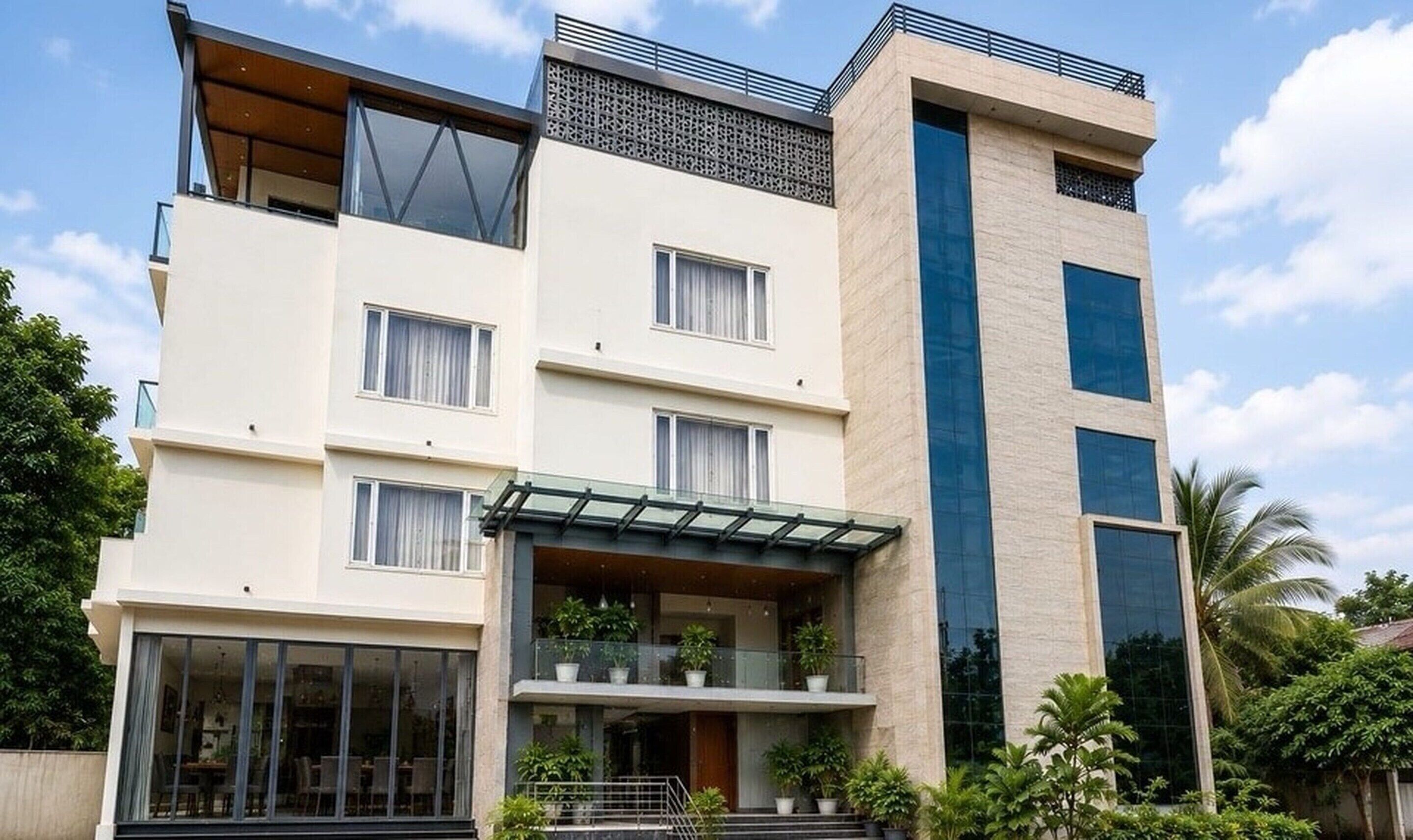 A multi-story building with a flat roof, large windows, and a balcony with potted plants.