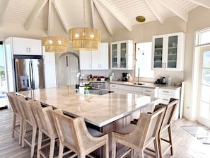 Un'ampia cucina con una grande isola, mobili bianchi e un lampadario.