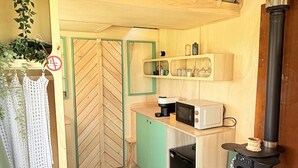 Una cocina compacta con microondas, cafetera y estufa de leña.