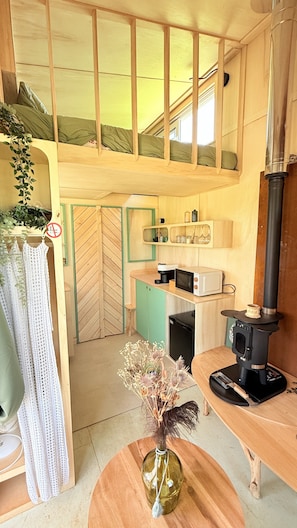A compact kitchen with a microwave, a coffee maker, and a wood-burning stove.