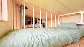 A single bed with a green bedspread in a room with wooden walls and a sloped ceiling. - Unique Accommodations (Montrieux-en-Sologne)
