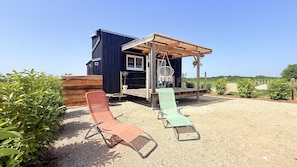 A wooden building with a porch and a covered seating area.
