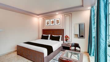 A hotel room with a bed, bedside table, mirror, and a small seating area with a glass table.