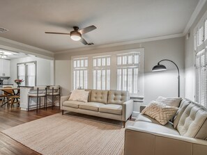 Ein geräumiges Wohnzimmer mit einem beigefarbenen Sofa, einem Couchtisch und einem Essbereich mit Tisch und Stühlen.
