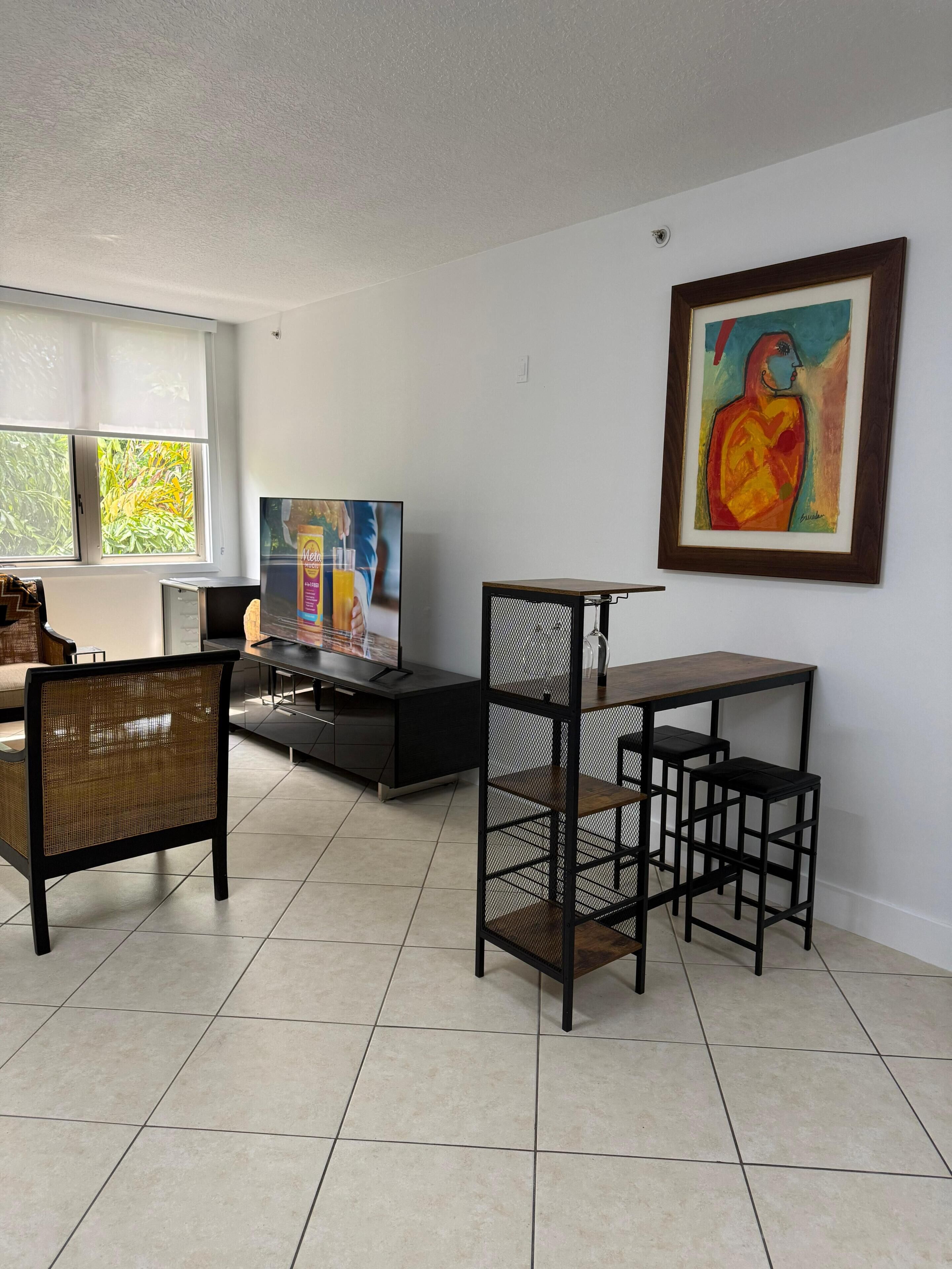 Un salon avec un téléviseur, un tableau encadré, une table à manger et une chaise.