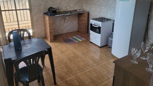 A compact kitchen with a gas stove, a refrigerator, a sink, and a dining area with a table and chairs.