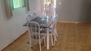 A dining area with a table and chairs, a window with blinds, and a view of the outside.