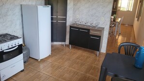A compact kitchen with a gas stove, refrigerator, and a small dining area with a table and chairs.