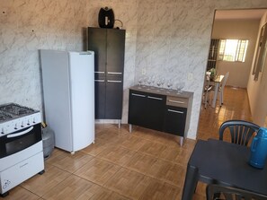 A compact kitchen with a gas stove, refrigerator, and a small dining area with a table and chairs.