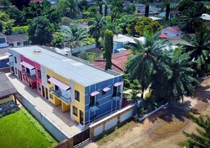 Un edificio de varios pisos con balcones, rodeado de vegetación y palmeras.