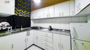 A modern kitchen with white cabinets, a black and yellow patterned curtain, a sink, a stove, and a refrigerator.