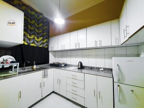 Una cocina moderna con gabinetes blancos, una cortina estampada en negro y amarillo, un fregadero, una estufa y un refrigerador.