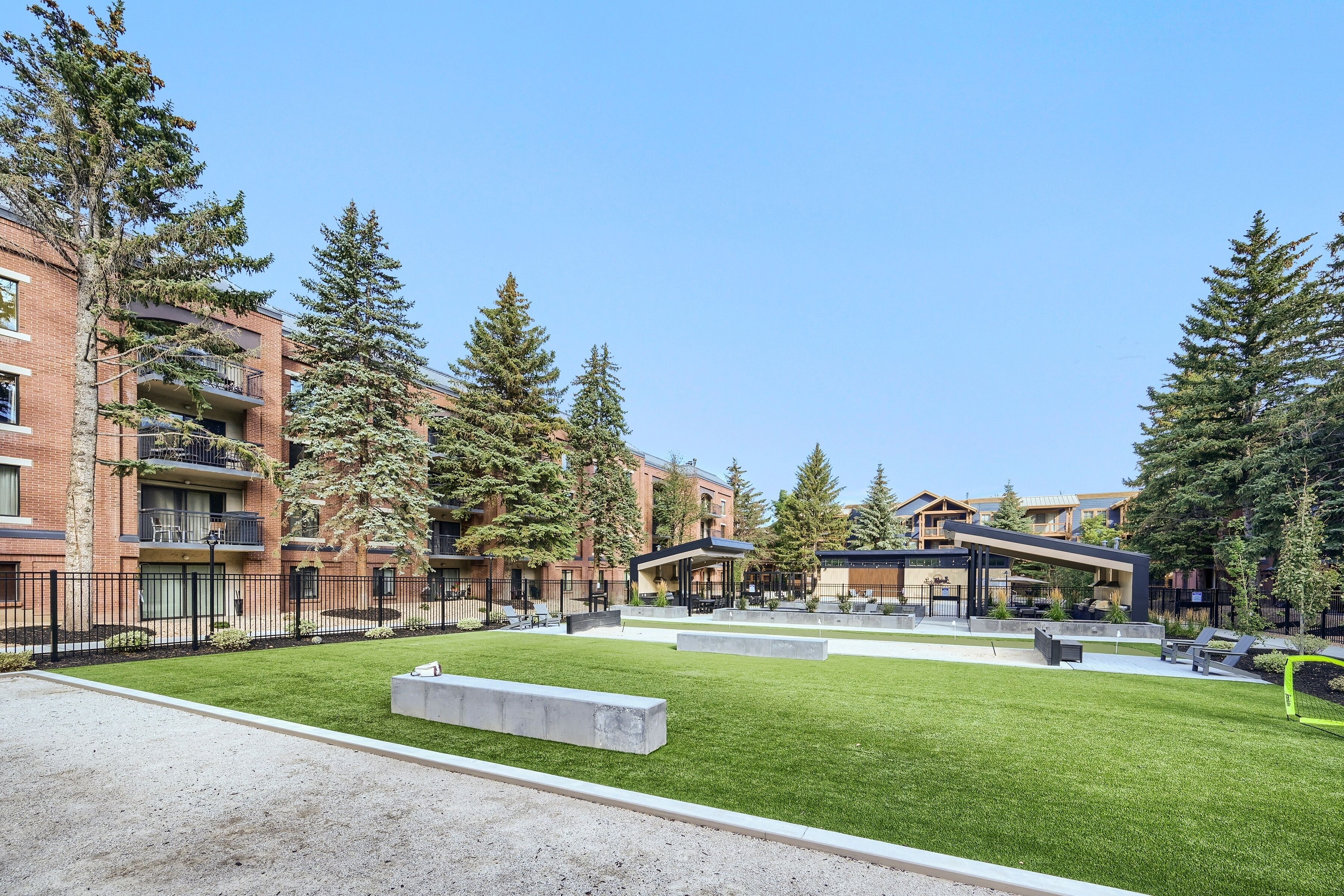 Un edificio residencial con varios pisos, zonas de estar al aire libre y un césped bien cuidado.