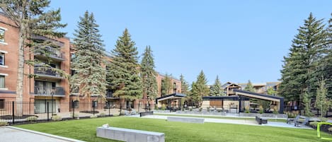 Un edificio residencial con varios pisos, zonas de estar al aire libre y un césped bien cuidado.