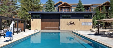 Una piscina con sillones de descanso y un edificio con el logotipo de un complejo de esquí.