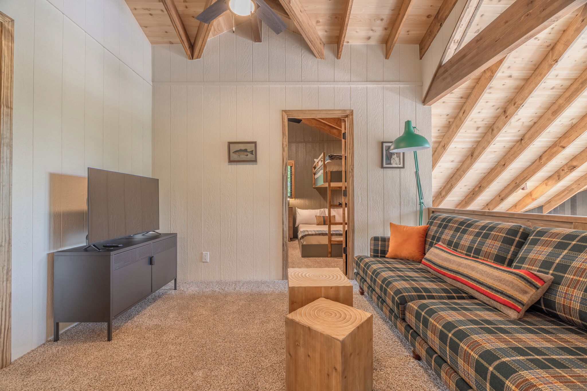 Una habitación acogedora con sofá, televisión, aparador de madera y ventilador de techo.