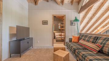 Una habitación acogedora con sofá, televisión, aparador de madera y ventilador de techo.